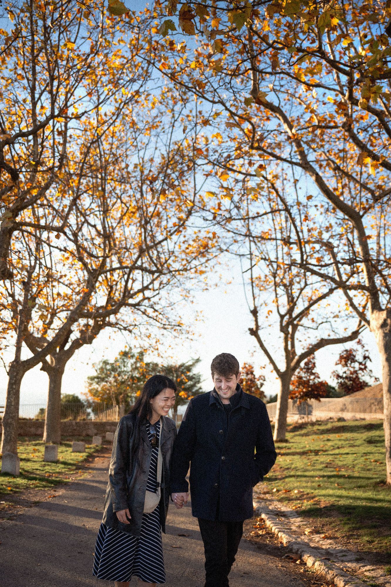 A couple walking beneath orange and yellow leaves during a fall photoshoot in the South of France.