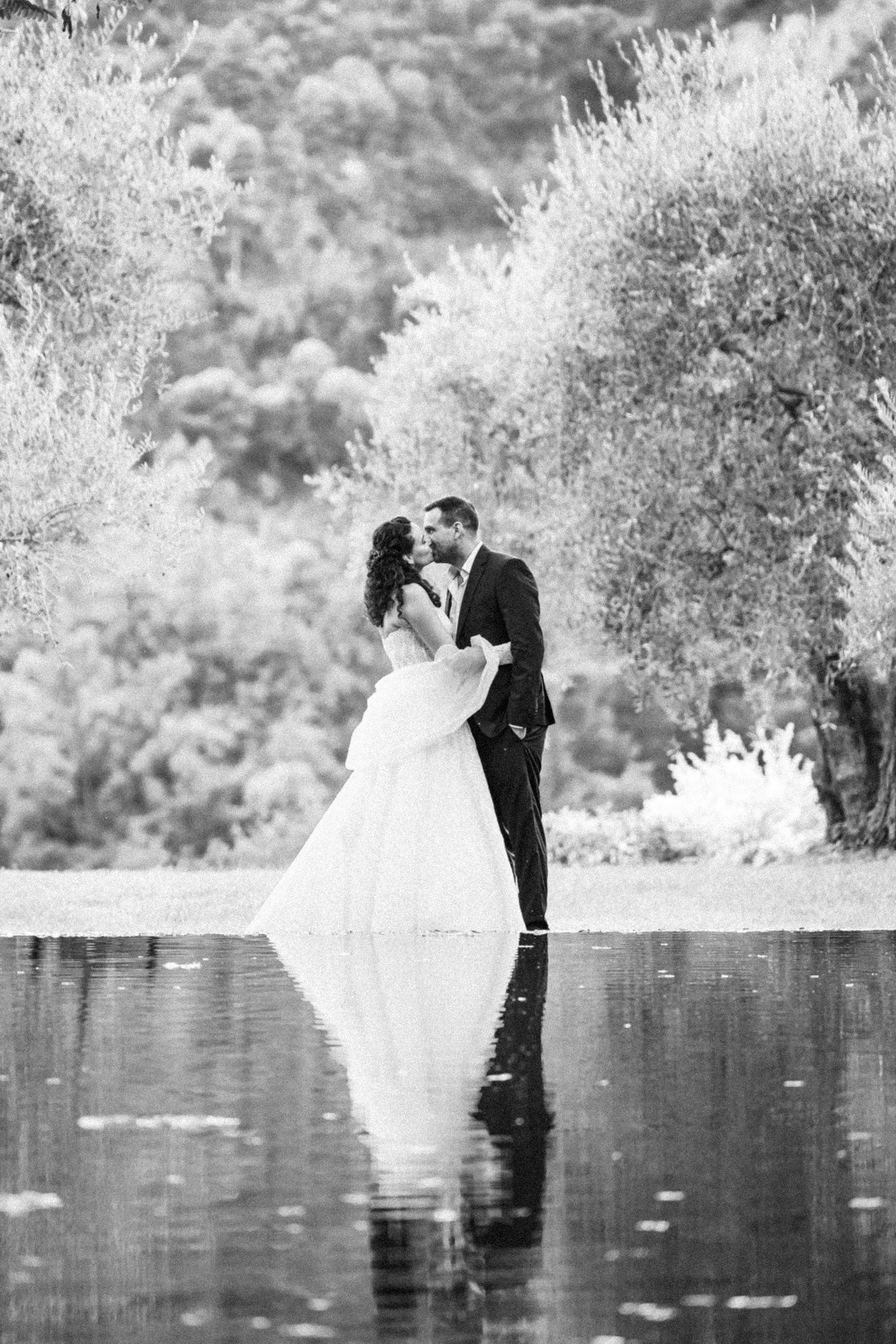 Un couple de mariés s'embrasse et se reflète dans le lac du Domaine de Riodam.