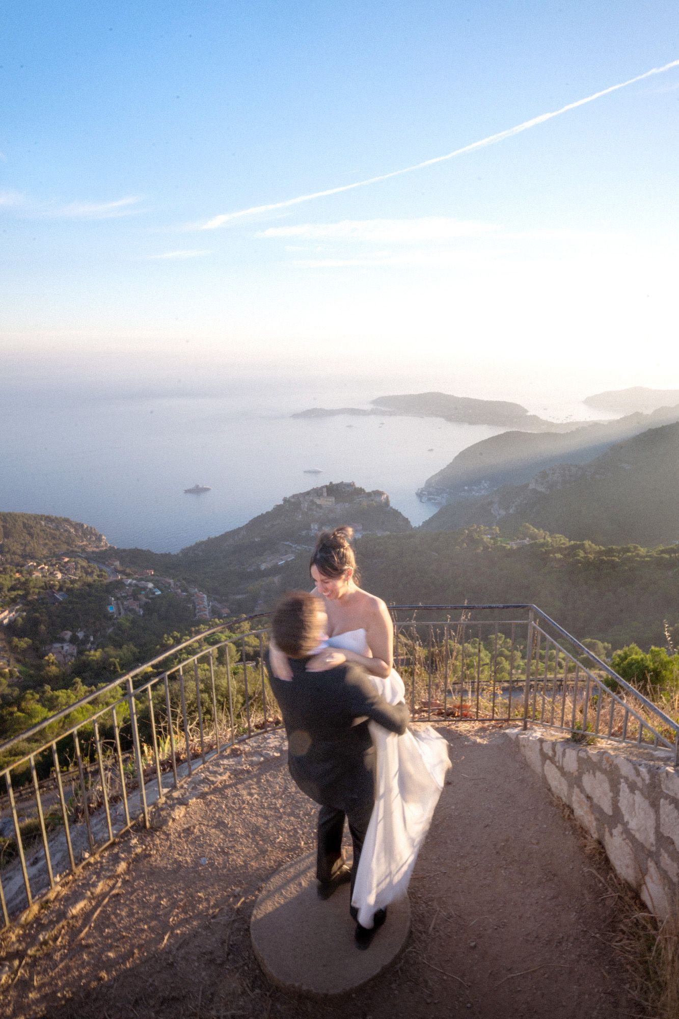 A couple spinning with motion blur during an elopement ceremony with a panoramic view of the sea behind them.