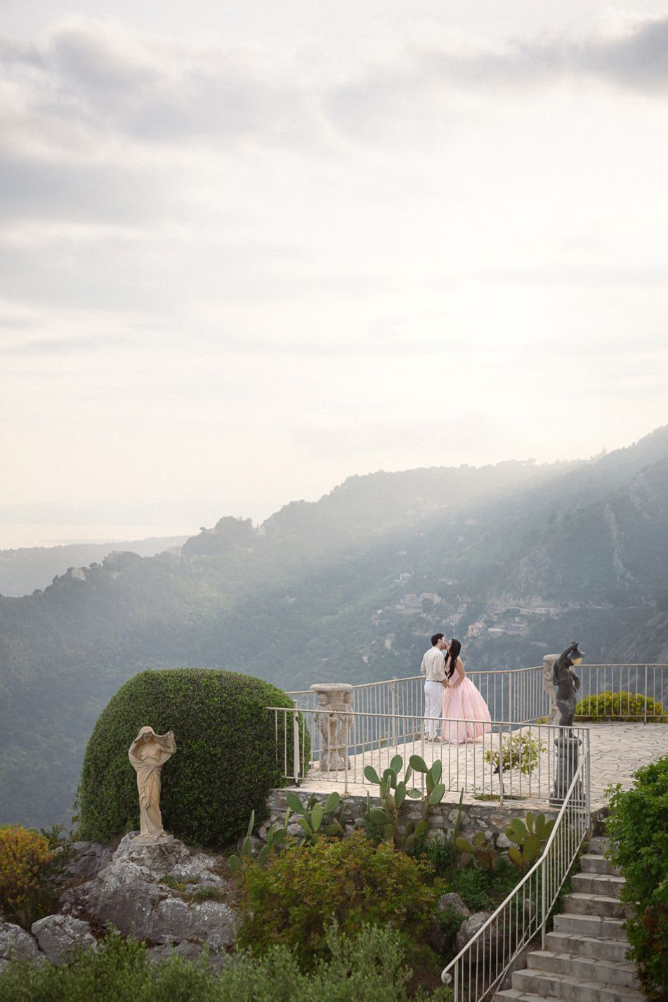 A wide angle image of a couple embracing during golden hour on the terraces of the Chevre d'Or after their engagement.