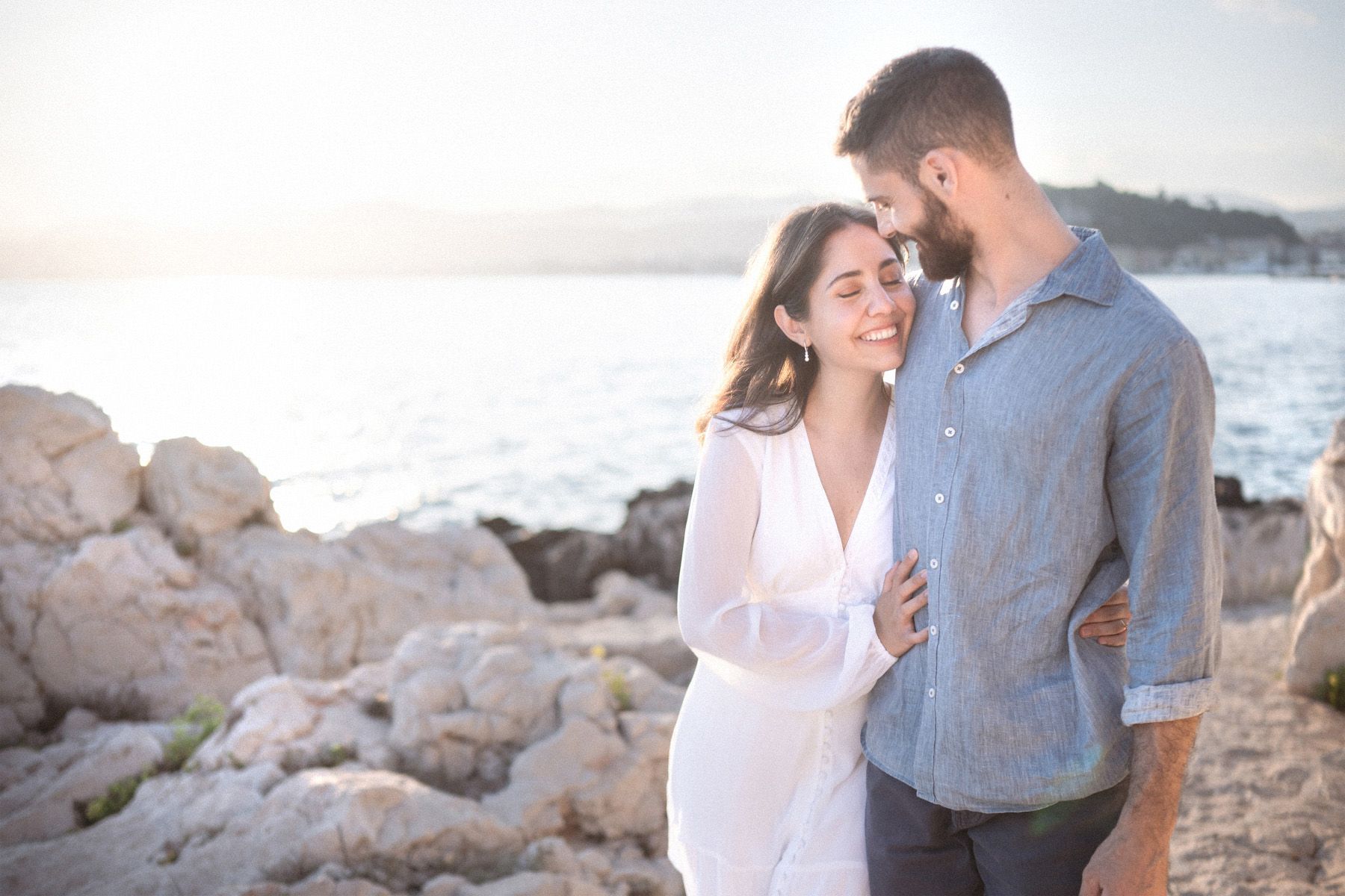 A couple laughing backlit by the sunset during a professional photography session in Nice, France.