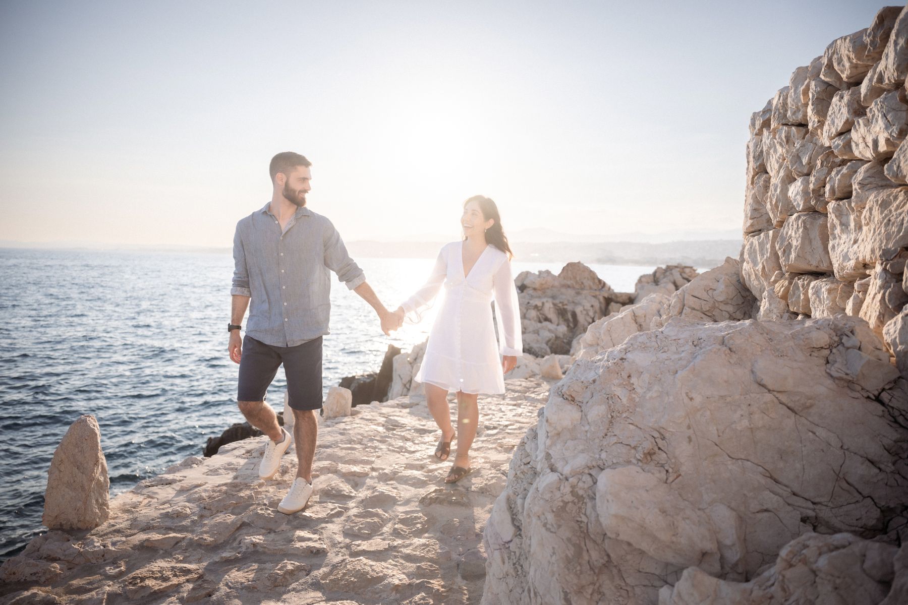 A couple laugh as they walk along the coastal path during a professional photography shoot.