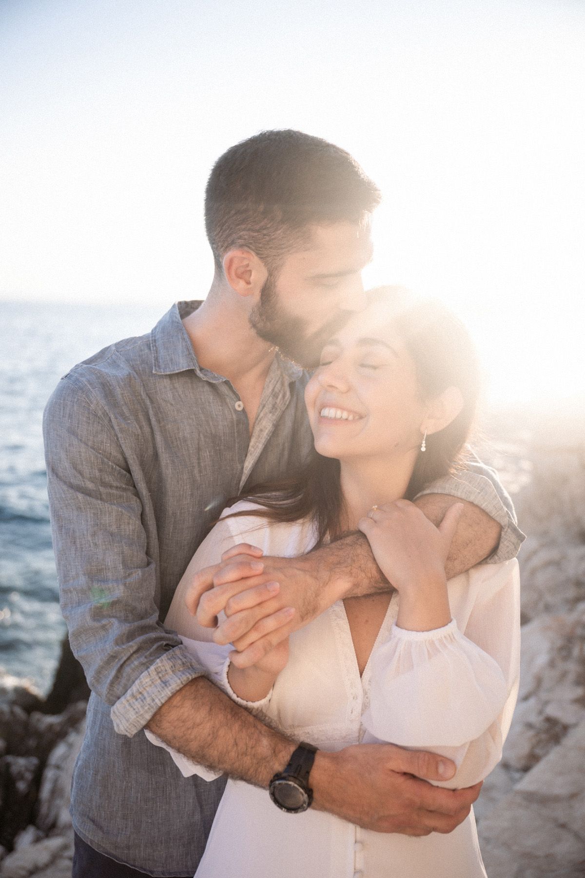 A couple laugh and hug during a professional photography shoot in Nice, France, to celebrate their engagement.