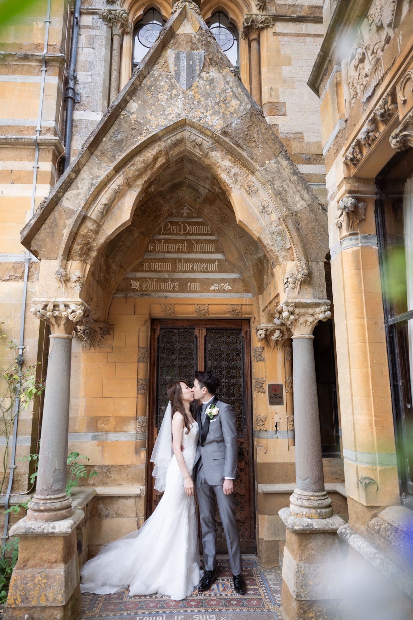 A wedded couple before the entrance of Ettington Park wedding venue