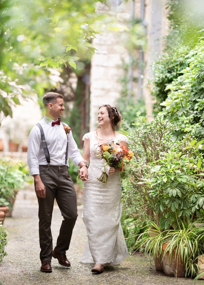 A coupe laugh and smile as they walk through St Paul de Vence on the day of their wedding