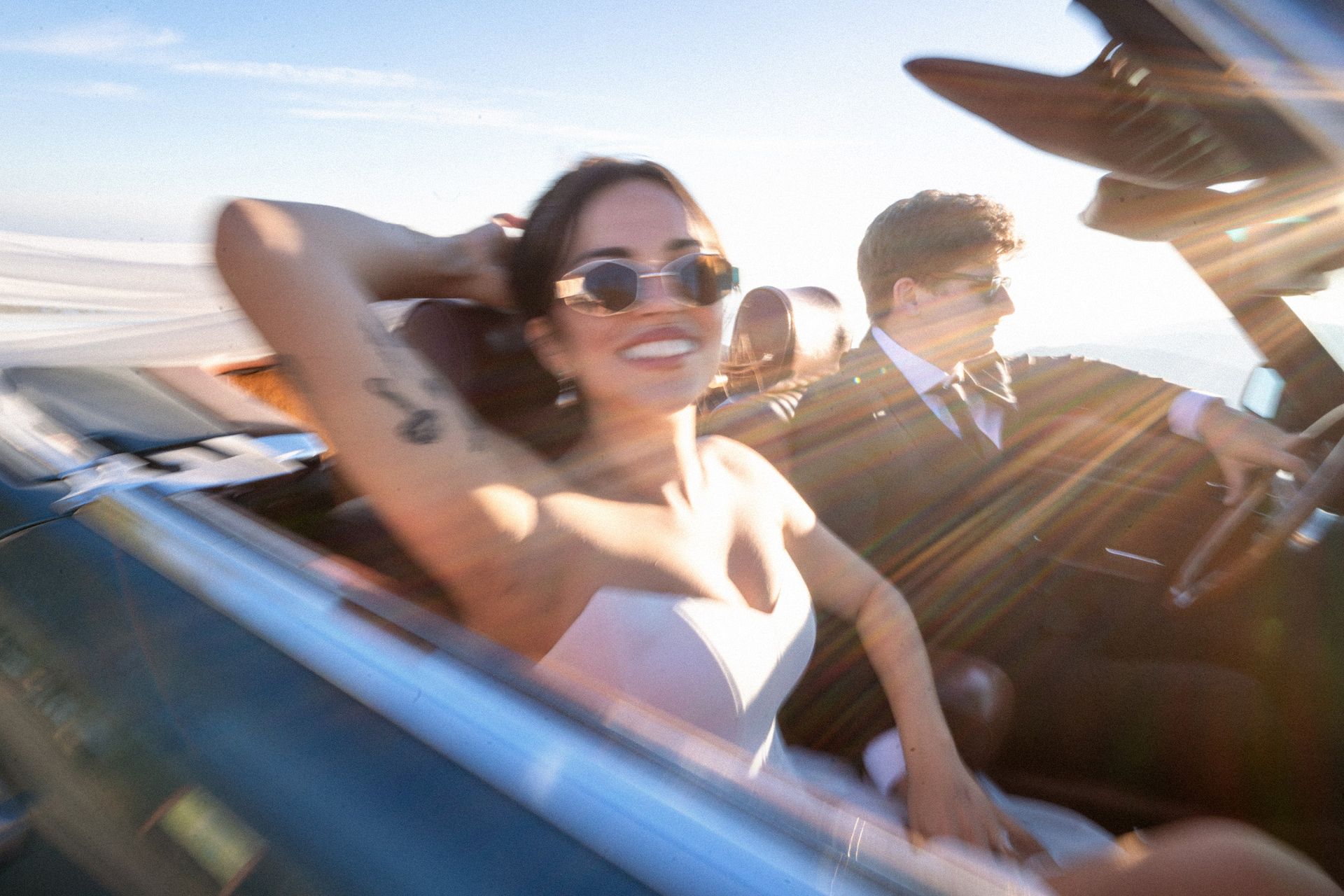 A wedded couple driving on the French Riviera in a convertible, vintage hire car.
