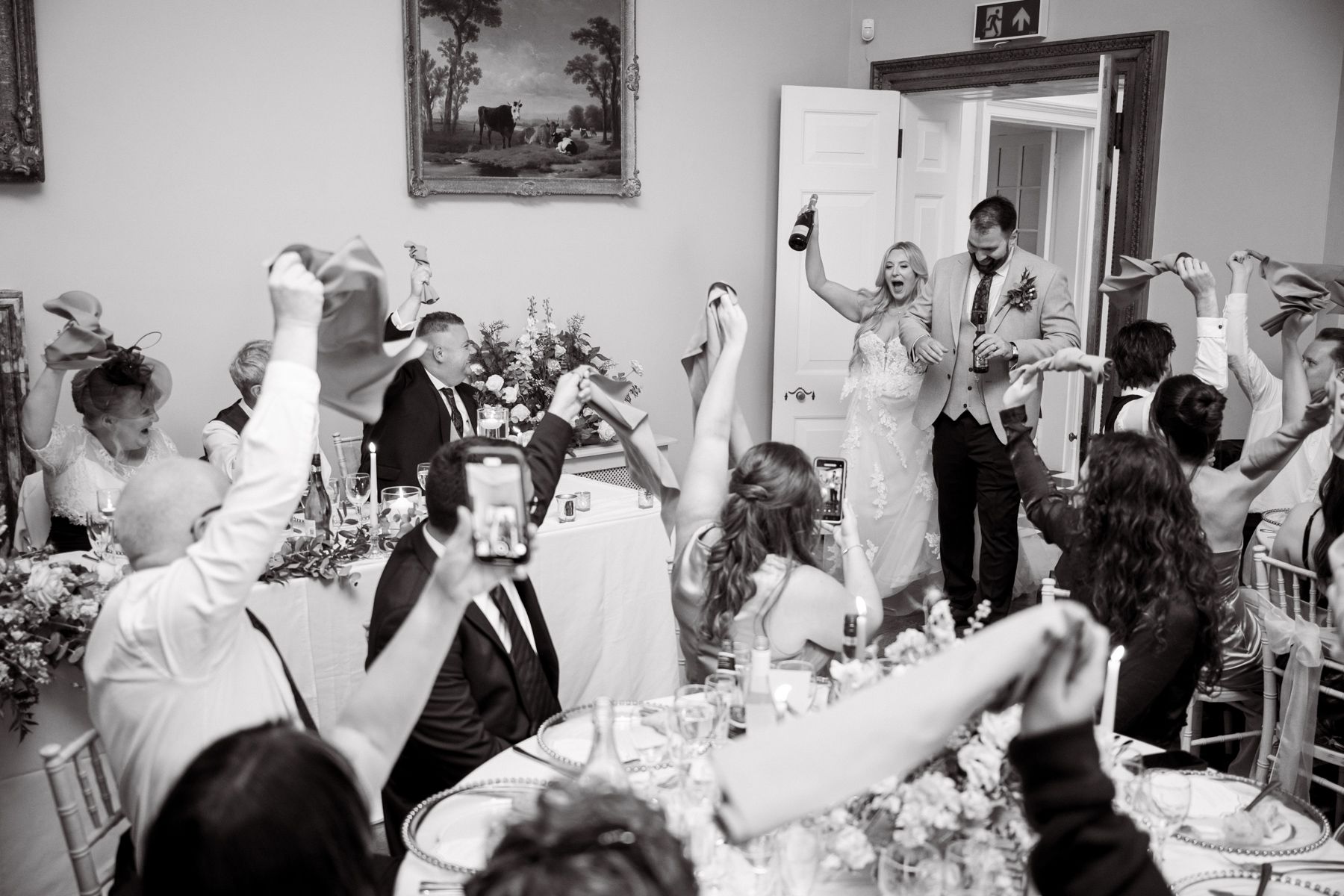 The bride and groom enter the dining room while white napkins are waved.