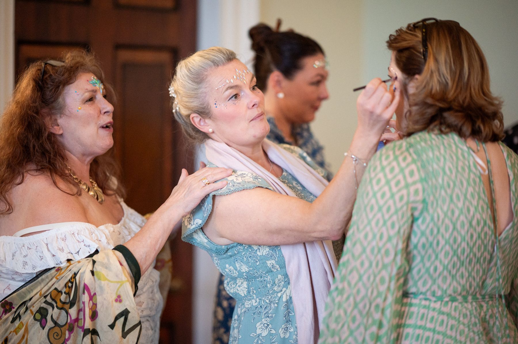 Wedding guests applying stick-on jewels and make-up before the evening celebrations begin.