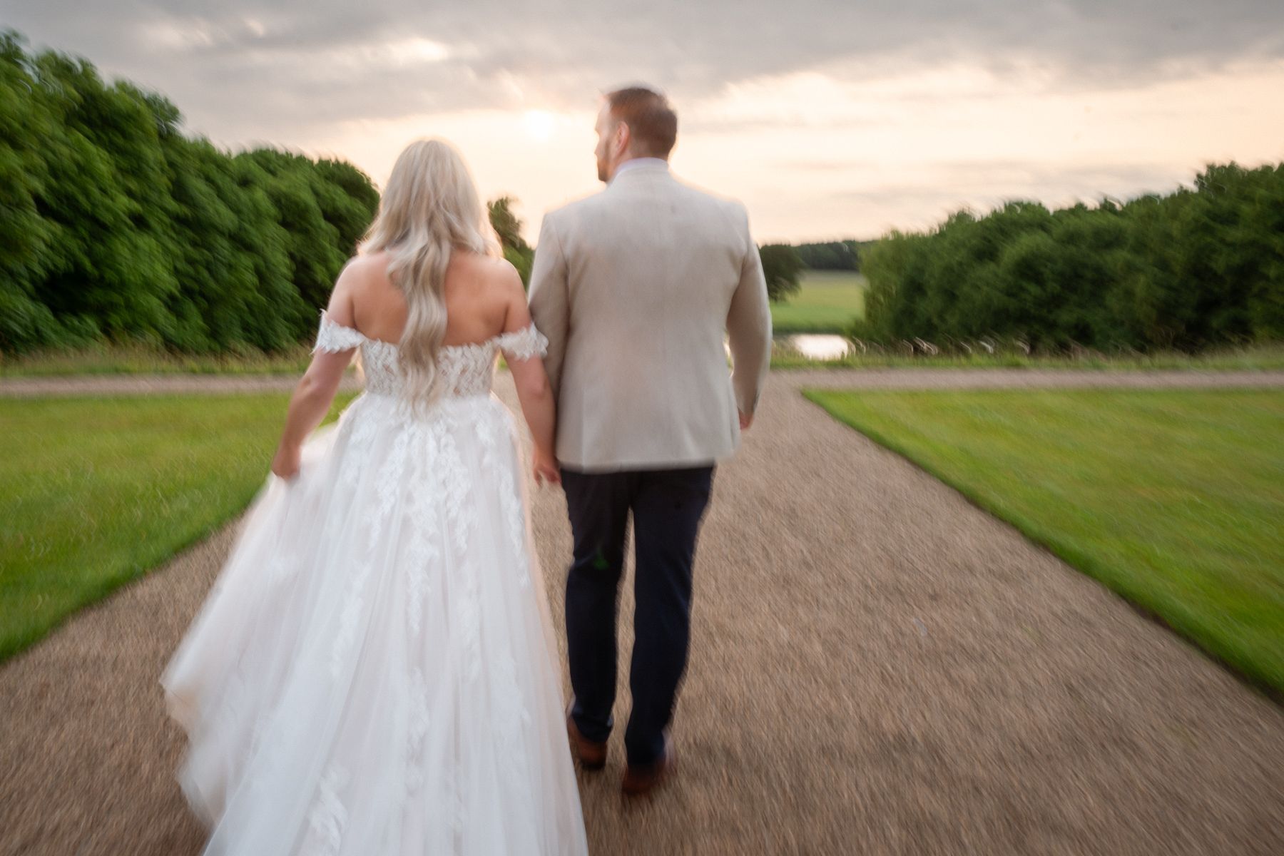 Slow shutter speed photograph of the trail of a wedding dress at sunset.