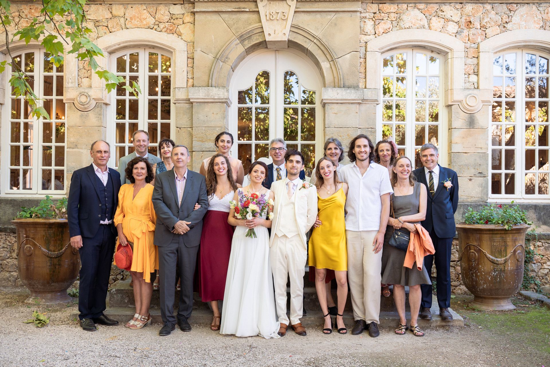 Une photo de groupe des invités au mariage prise dans le parc du Château Font du Broc.