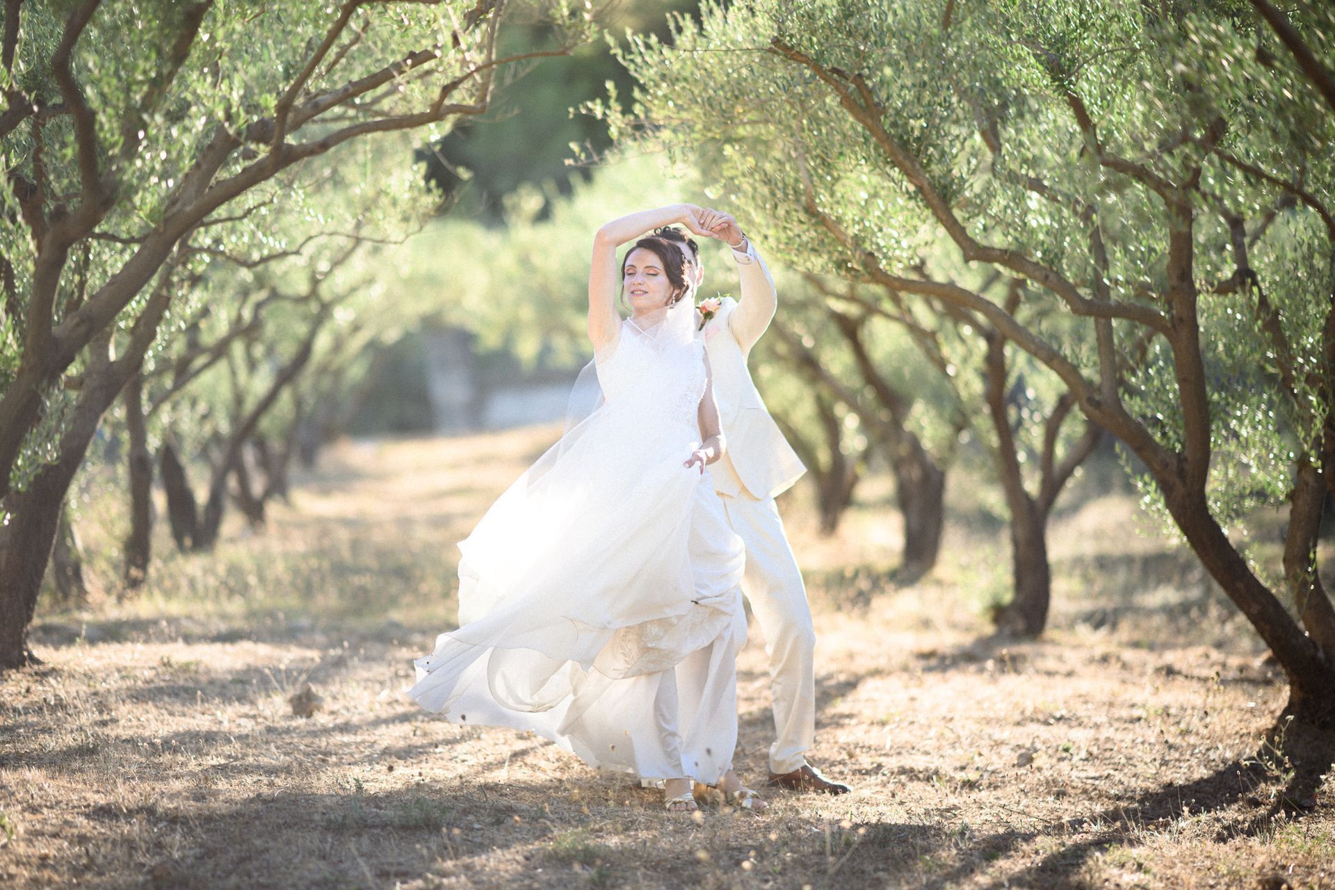 Un couple danse lors d'une séance photo naturelle, spontanée et improvisée le jour de leur mariage, dans une oliveraie provençale.