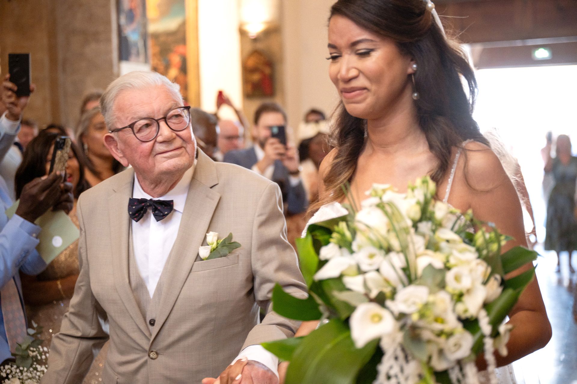 La mariée et son père remontent l'allée centrale.