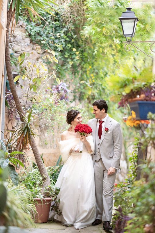A bride and groom smiling in a candid photo on their wedding day in a medieval French village.