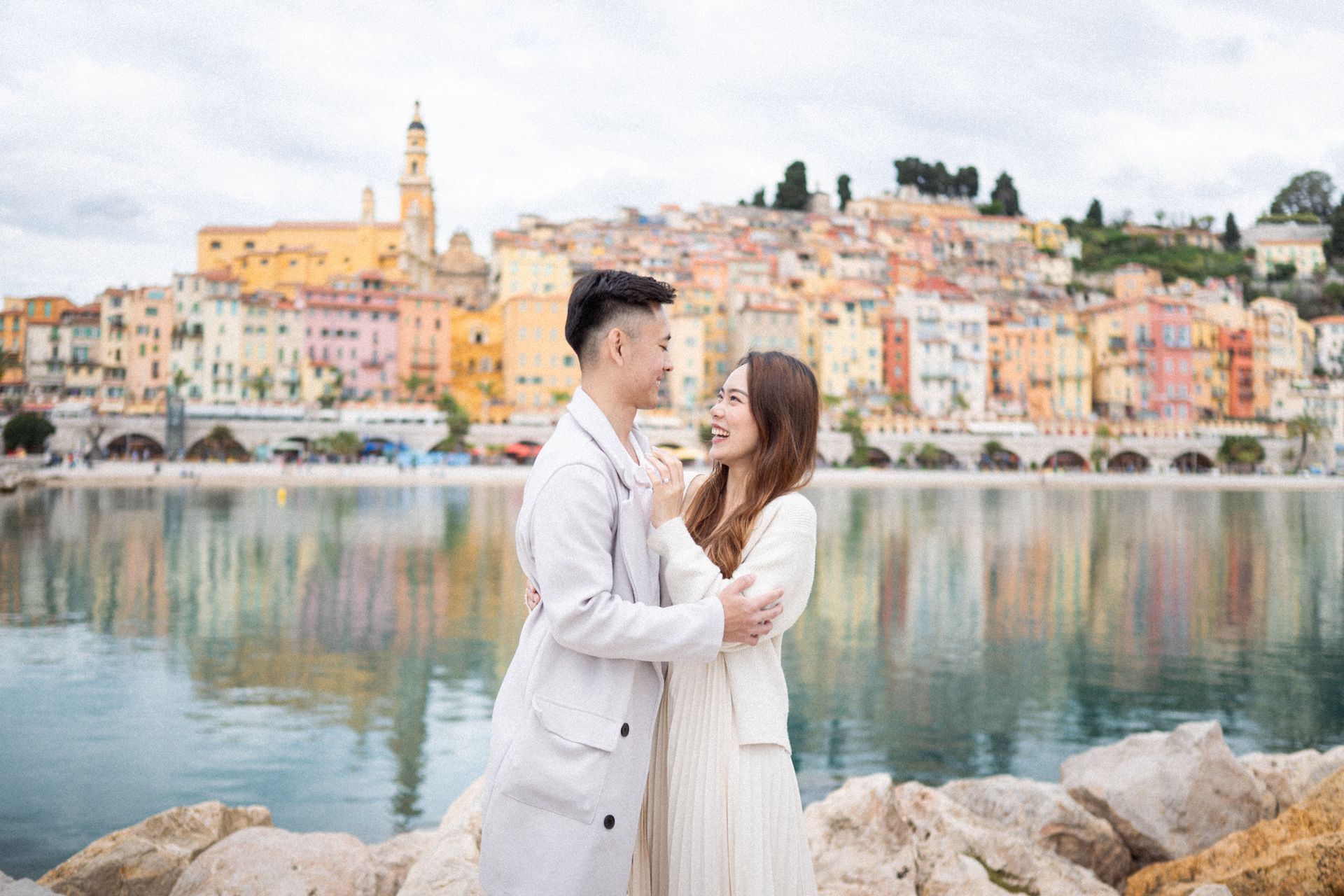 An engaged couple embrace before the famous Menton Panoramic viewpoint on the French Riviera.