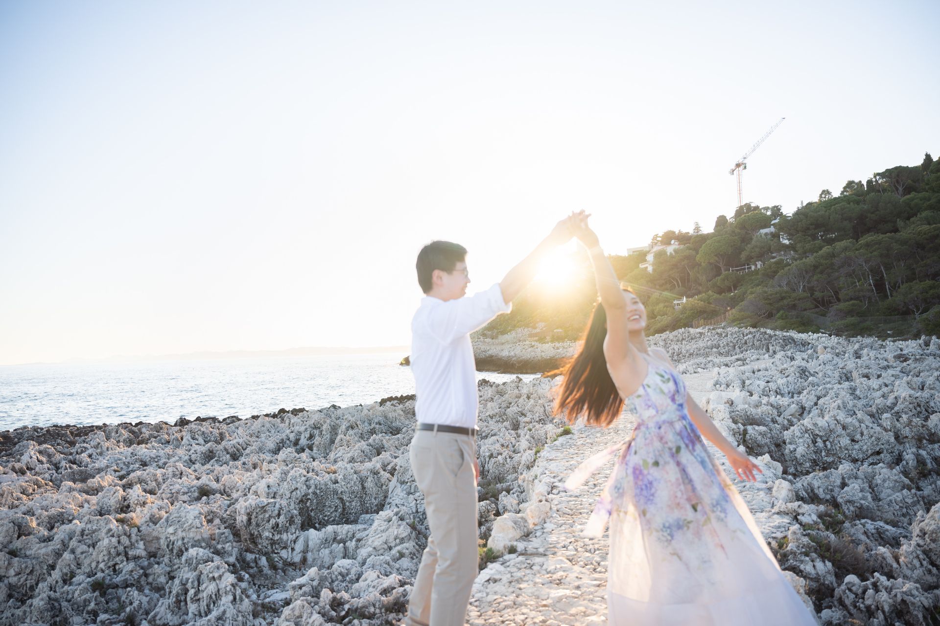 A couple laughing and dancing near a lighthouse at sunset in the south of France.