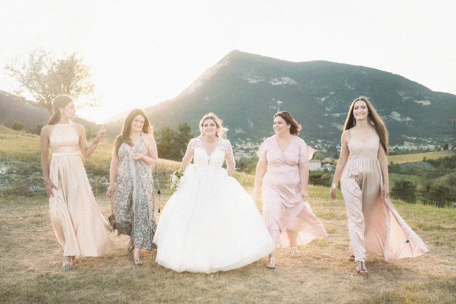 une mariée se promène avec les demoiselles d'honneur dans les Alpes françaises au coucher du soleil