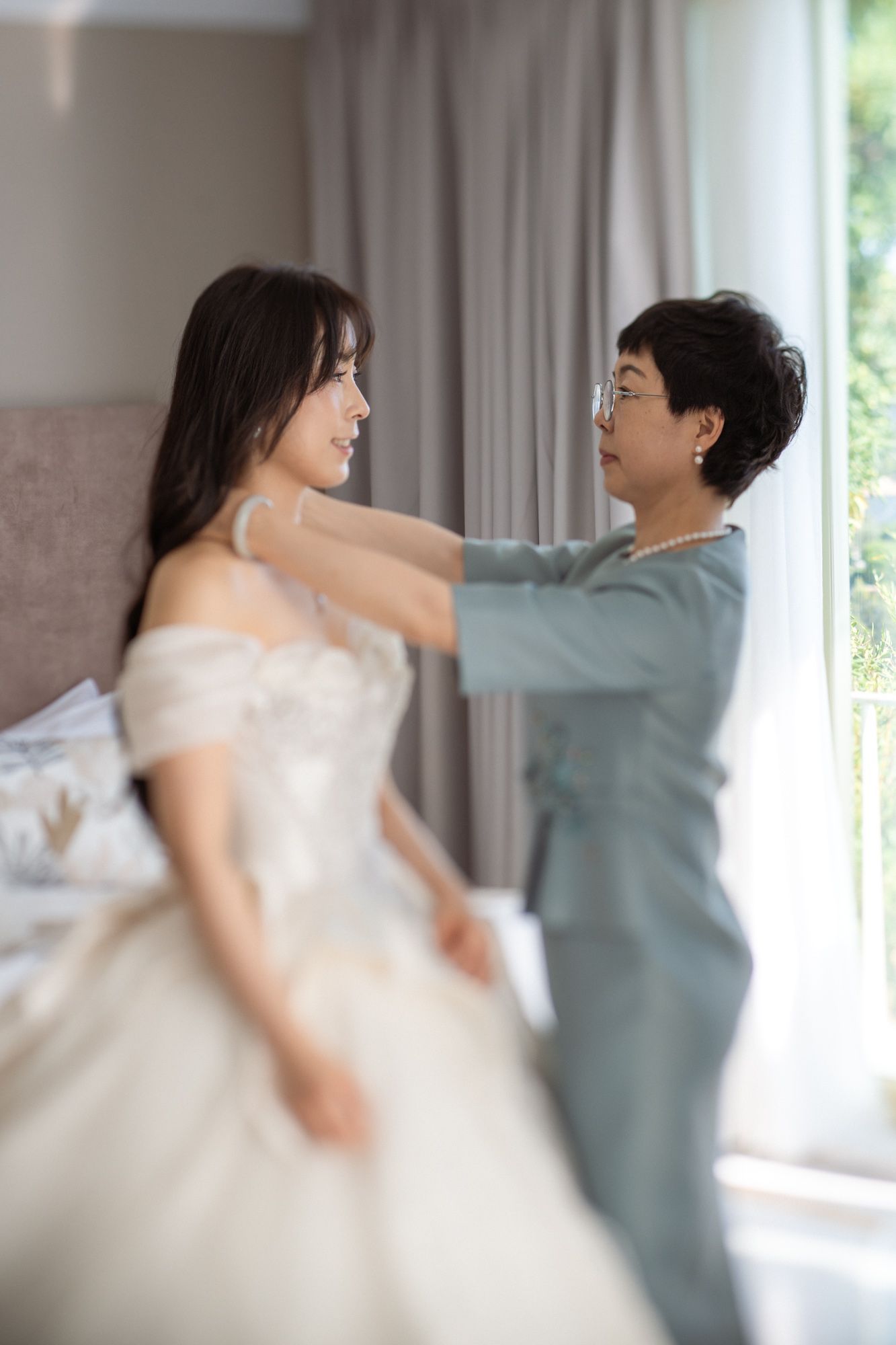 The bride's mother applies finishing touches to her daughter's dress