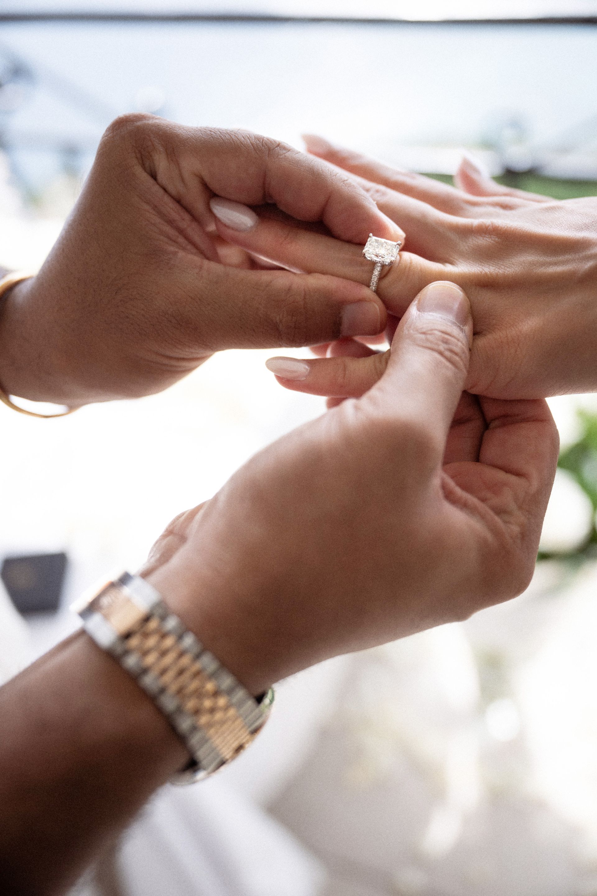 A man slides an engagement ring onto the hand of his fiancé.