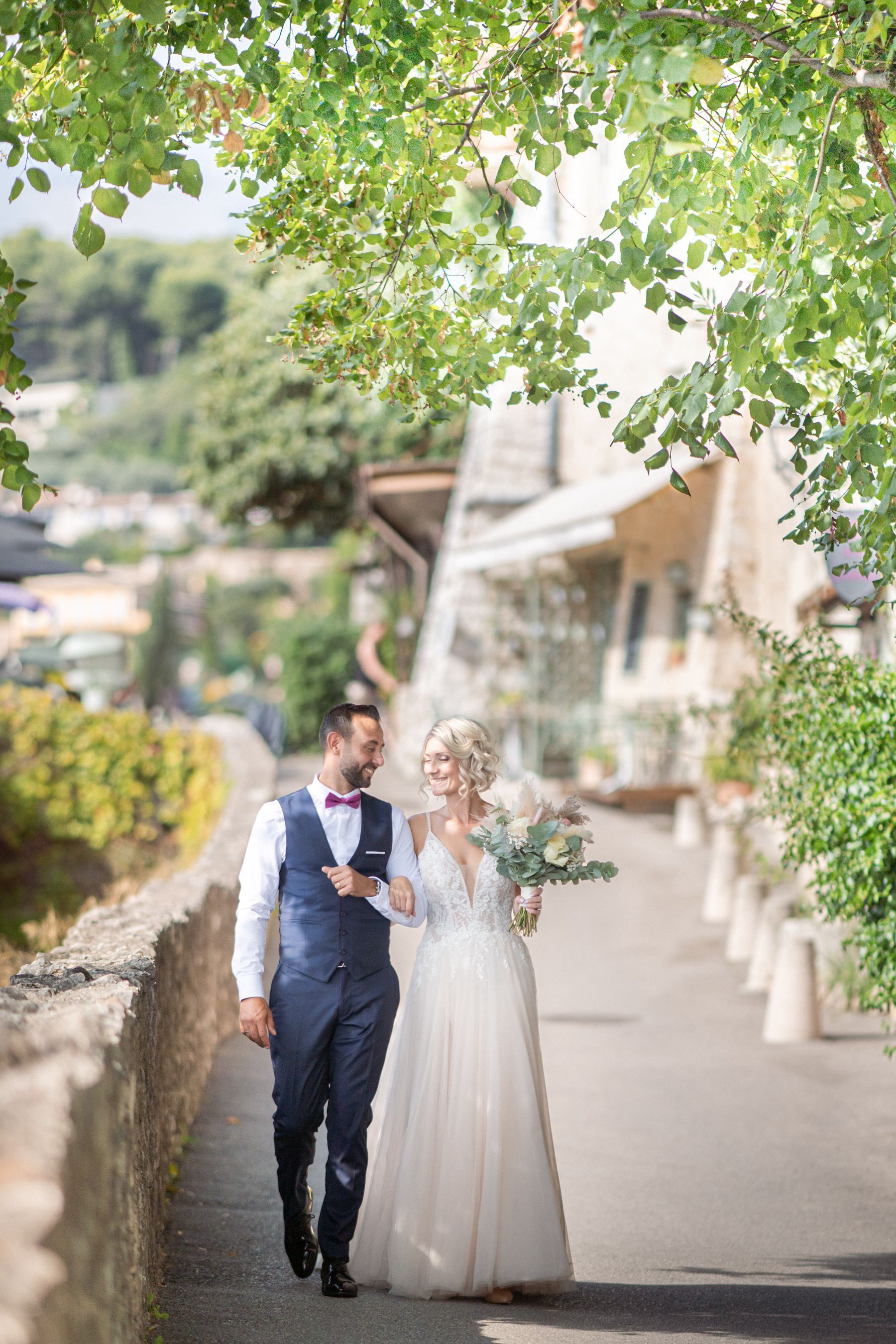 A couple in wedding attire wander through medieval streets in the South of France.