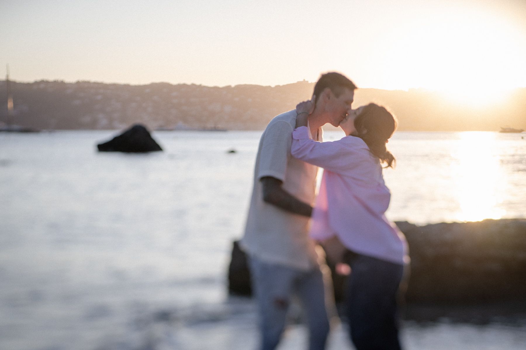 A maternity photoshoot showing a couple kissing at golden hour on the French Riviera.