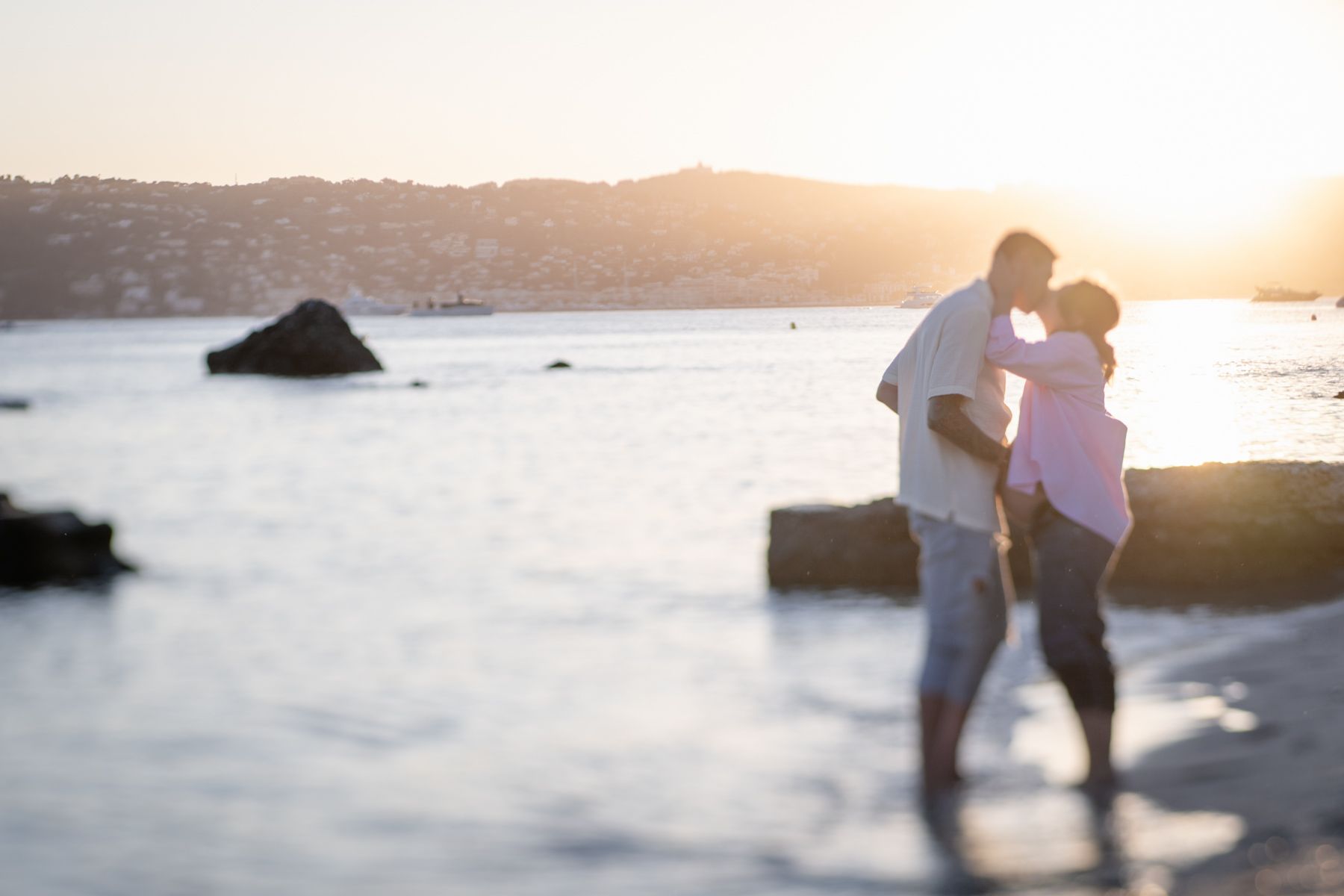 A maternity photoshoot showing a couple kissing at sunset on the French Riviera.