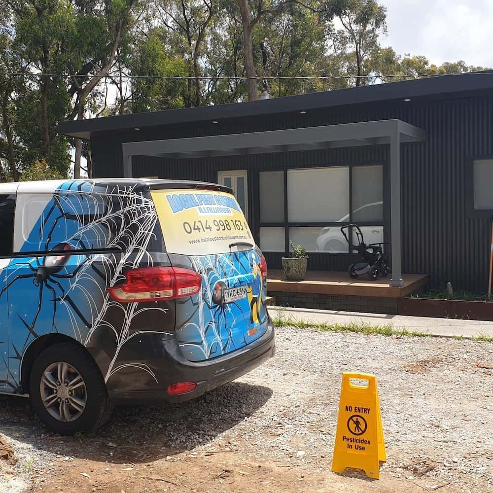 A Blue Van With A Spider Web On The Back Is Parked In Front Of A House — Local Pest Control Illawarra in Wollongong, NSW