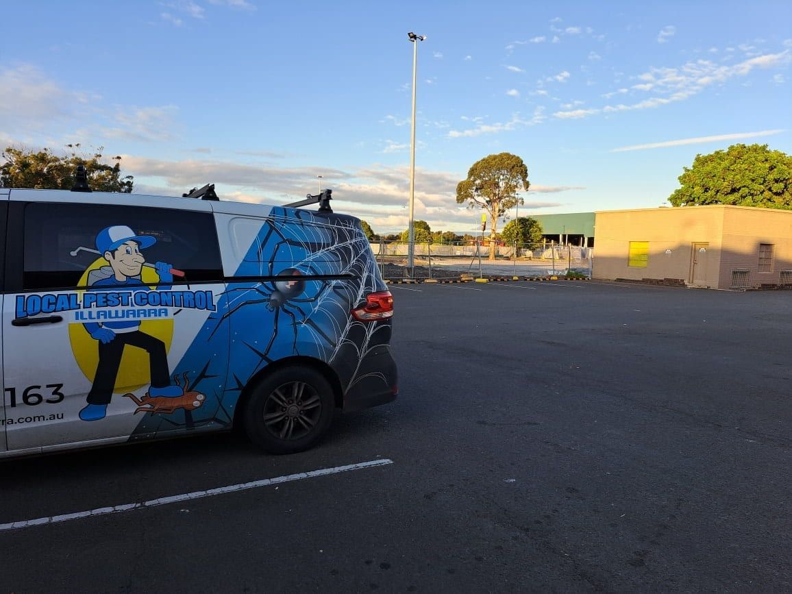 A White Van With A Cartoon Man On The Side Is Parked In A Parking Lot — Local Pest Control Illawarra in Albion Park, NSW