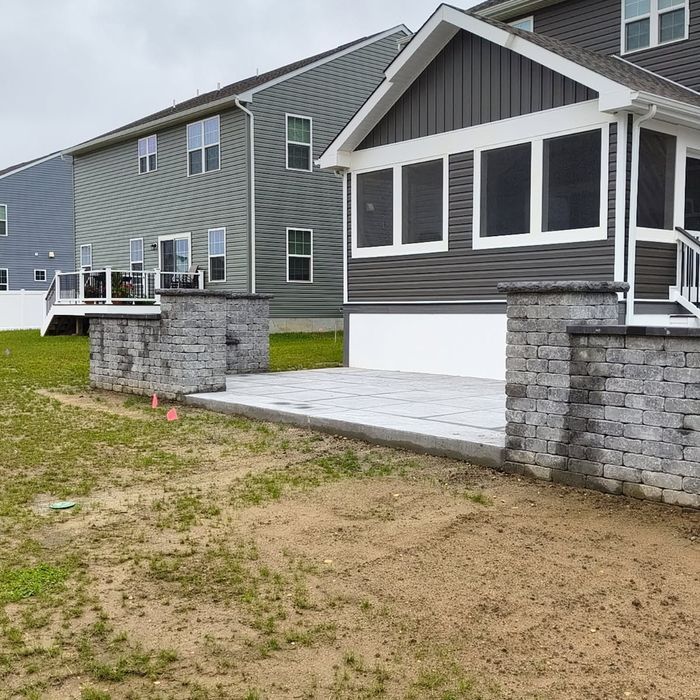 Wooden deck with steps leading to a back door of a house. Tools and materials are on the grass.