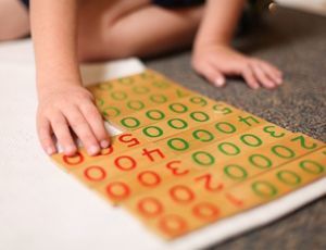 Child using Montessori decimal cards to explore quantity and place value through hands-on math work.