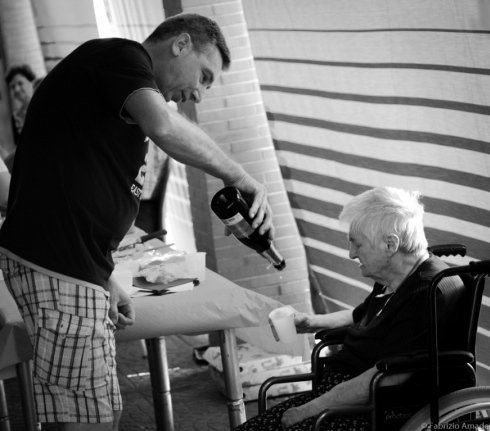 assistente versa da bere a una donna anziana
