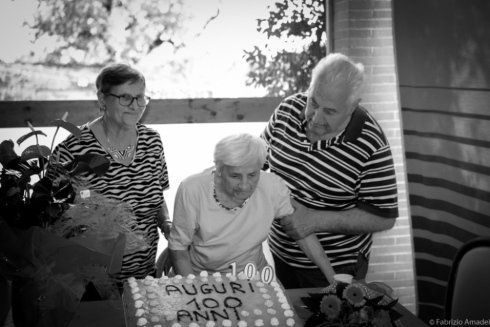 donna anziana soffia sulle candele della torta per i suoi 100 anni