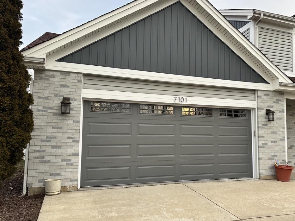 Suburban house exterior with gray garage door, stone siding, and front driveway