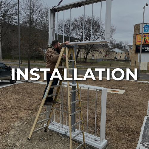 Man on a ladder installing a sign frame outdoors | custom signs conway arkansas