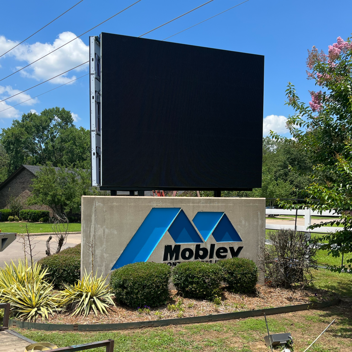 Moblev sign with blue logo, beneath a large, blank LED screen, outdoors | electronic signs