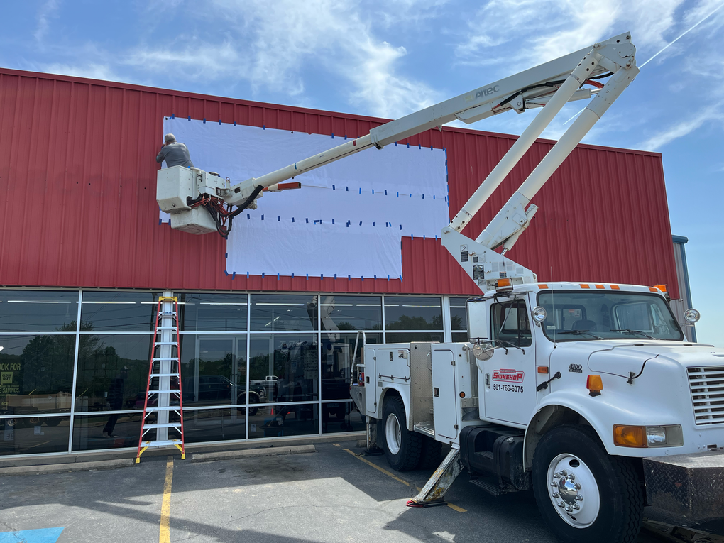 Truck with a lift and worker on a building installing a sign | metal business signs outdoor