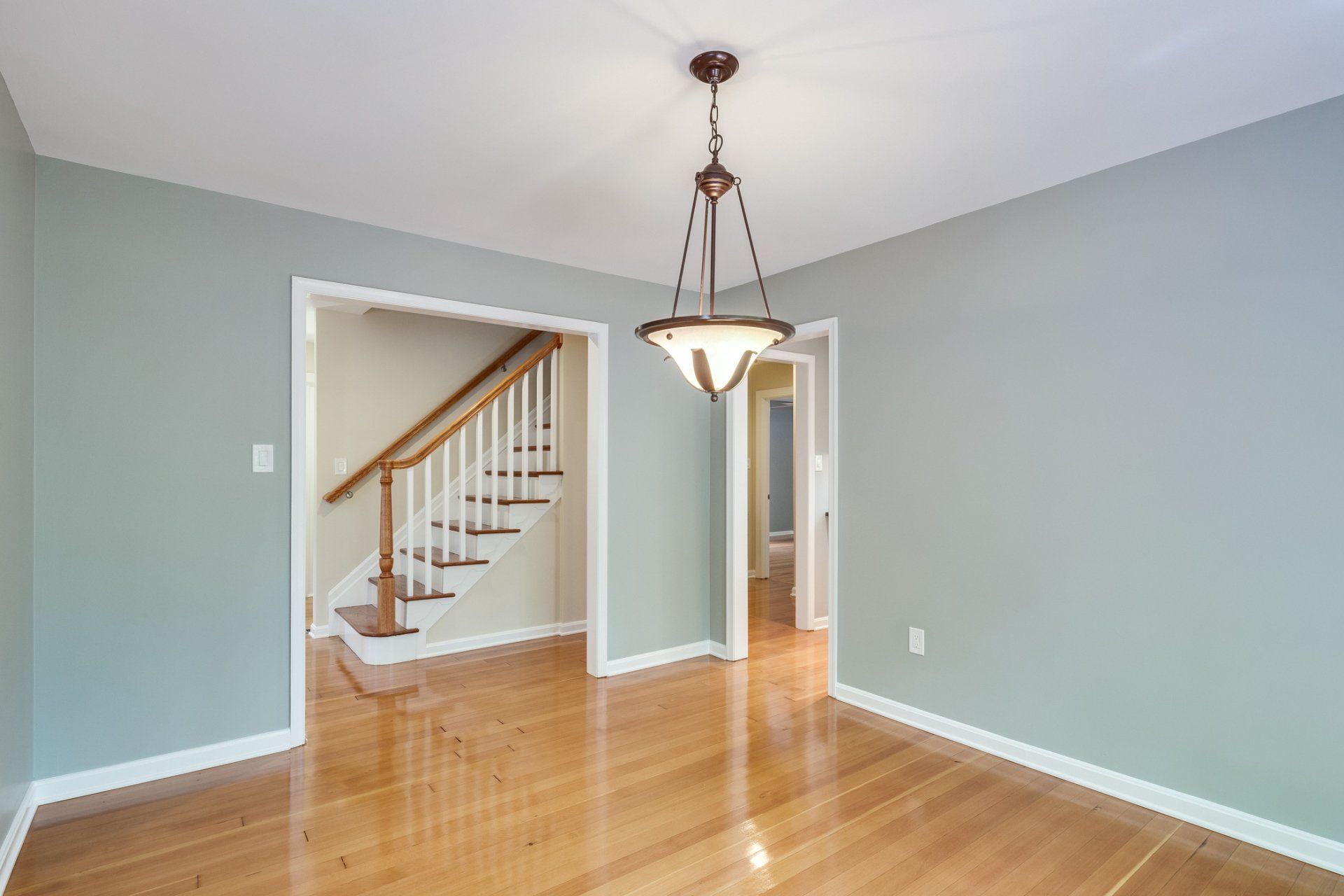 An empty dining room with hardwood floors and stairs
