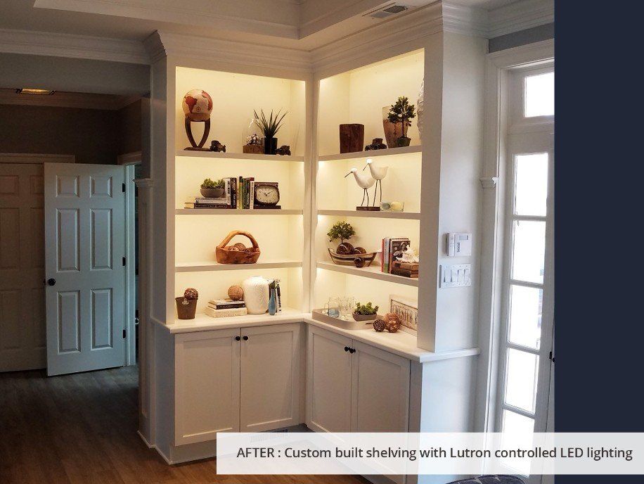 A living room with white cabinets and shelves with lights on them.