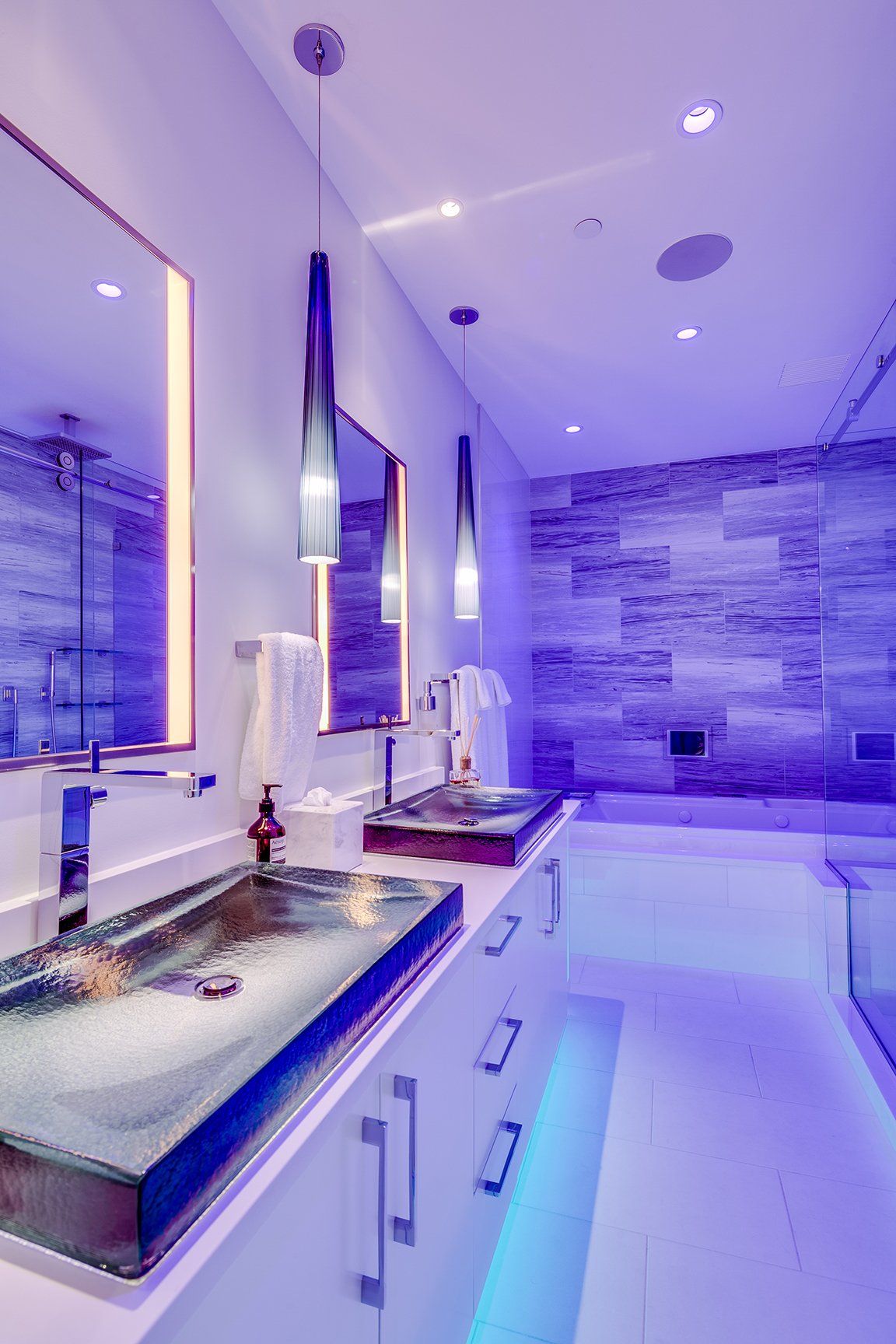 A bathroom with purple lights and a sink and mirror