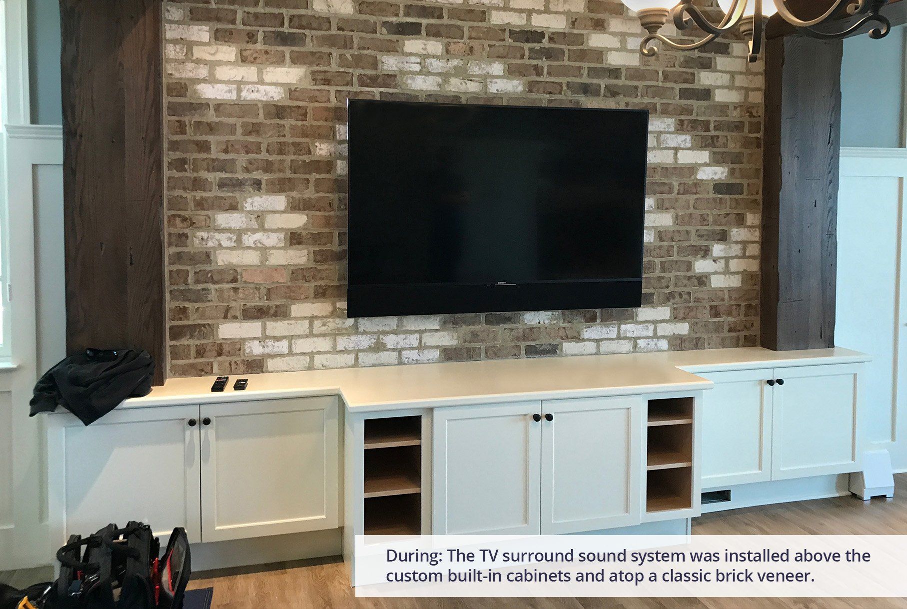 A living room with a brick wall and a flat screen tv mounted on it.