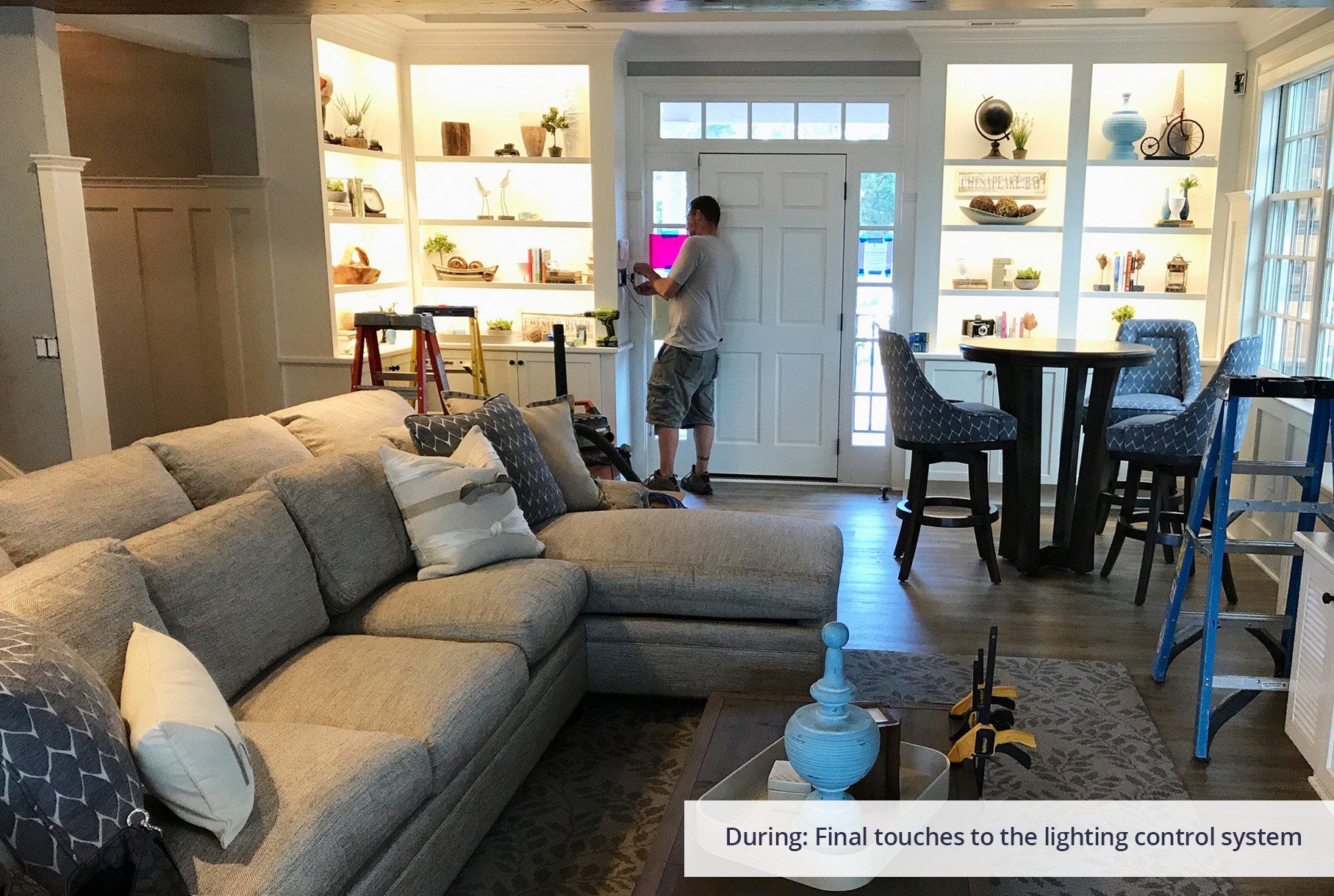 A man is standing in a living room with a couch and a table.