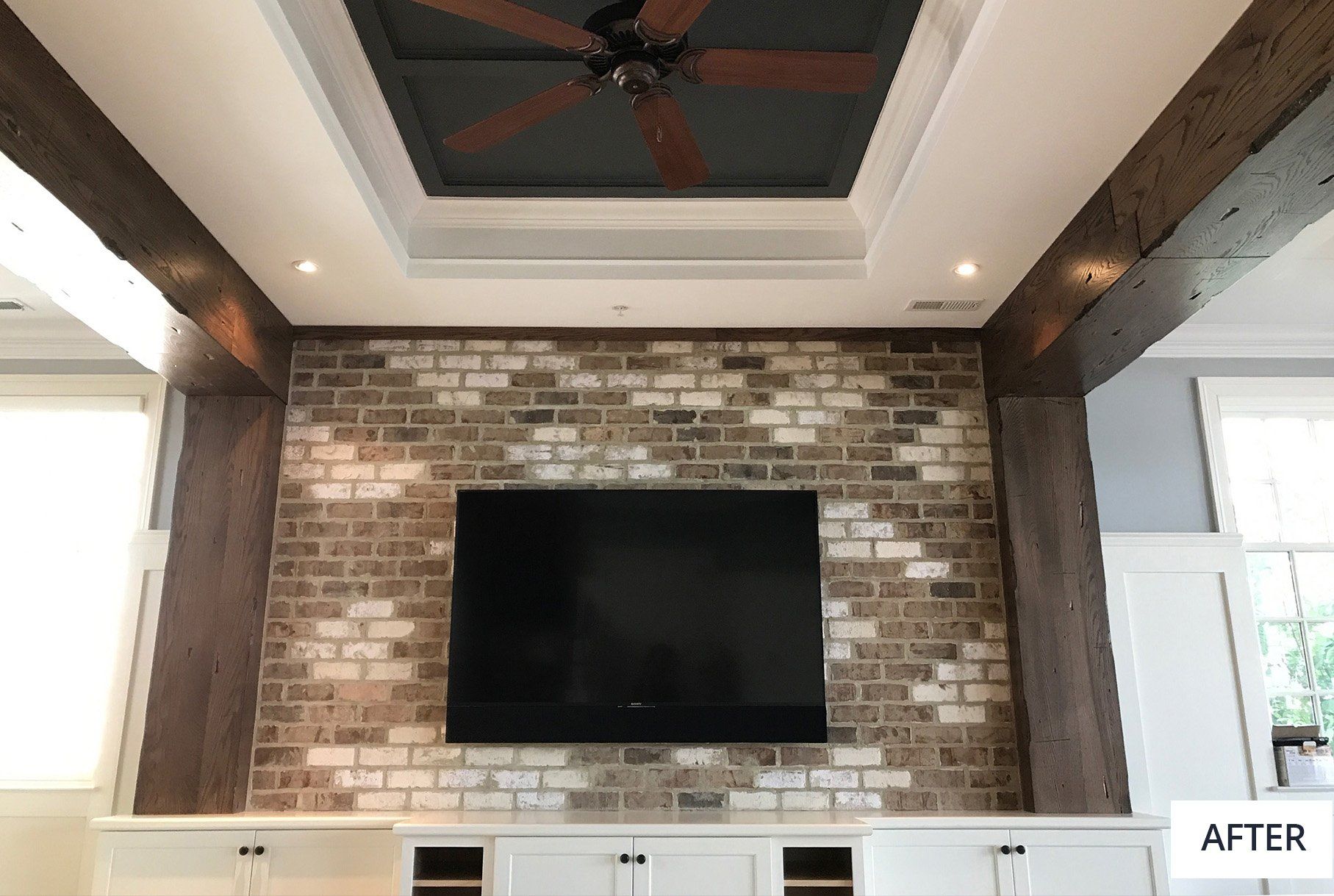 A living room with a ceiling fan and a flat screen tv on the wall.