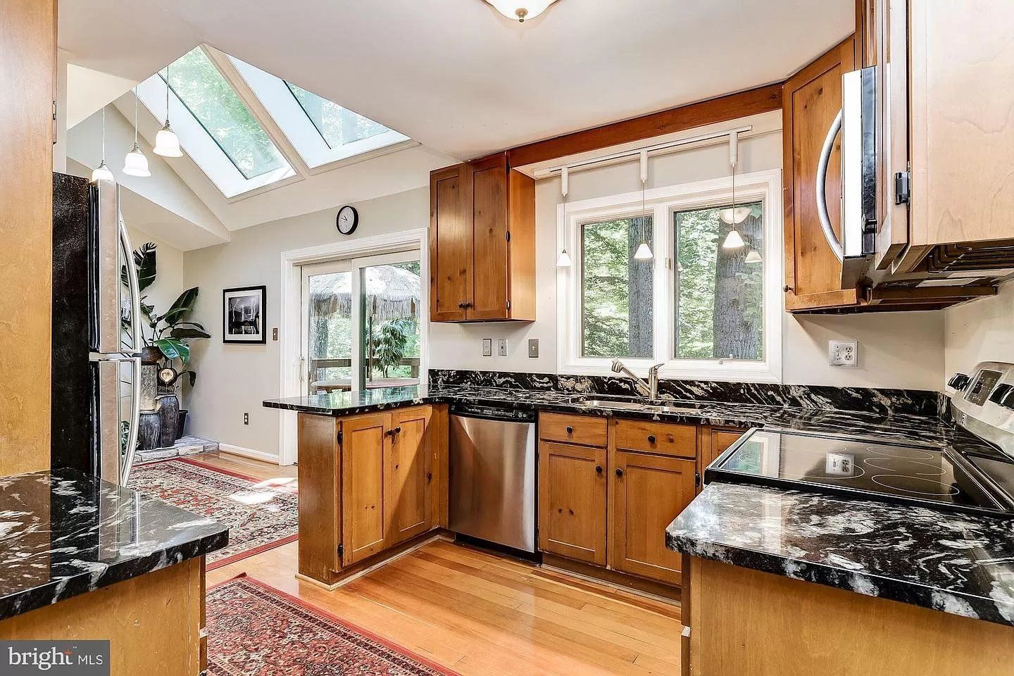 A kitchen with wooden cabinets , granite counter tops , stainless steel appliances and a skylight.
