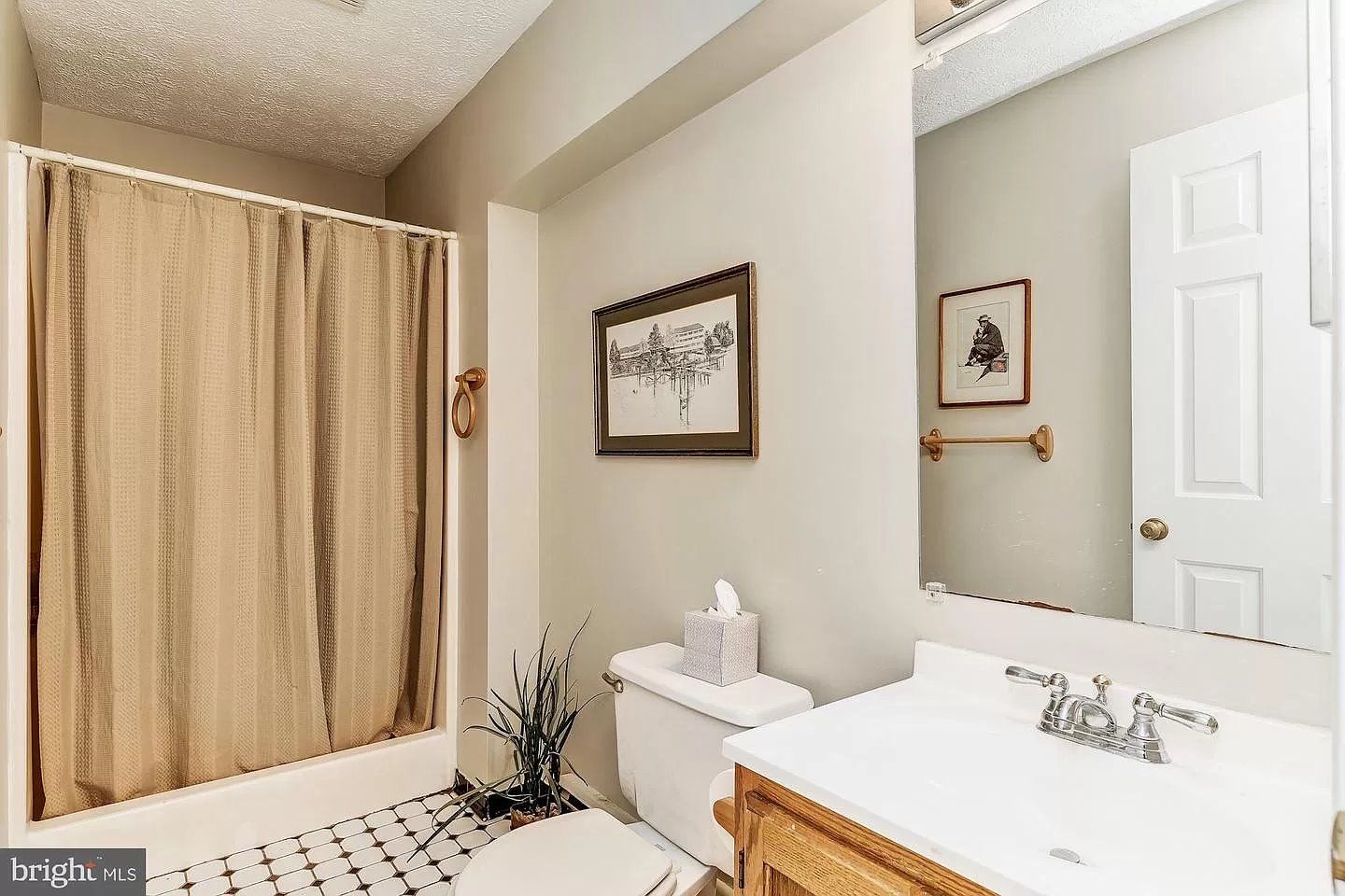 A bathroom with a toilet , sink , shower and mirror.