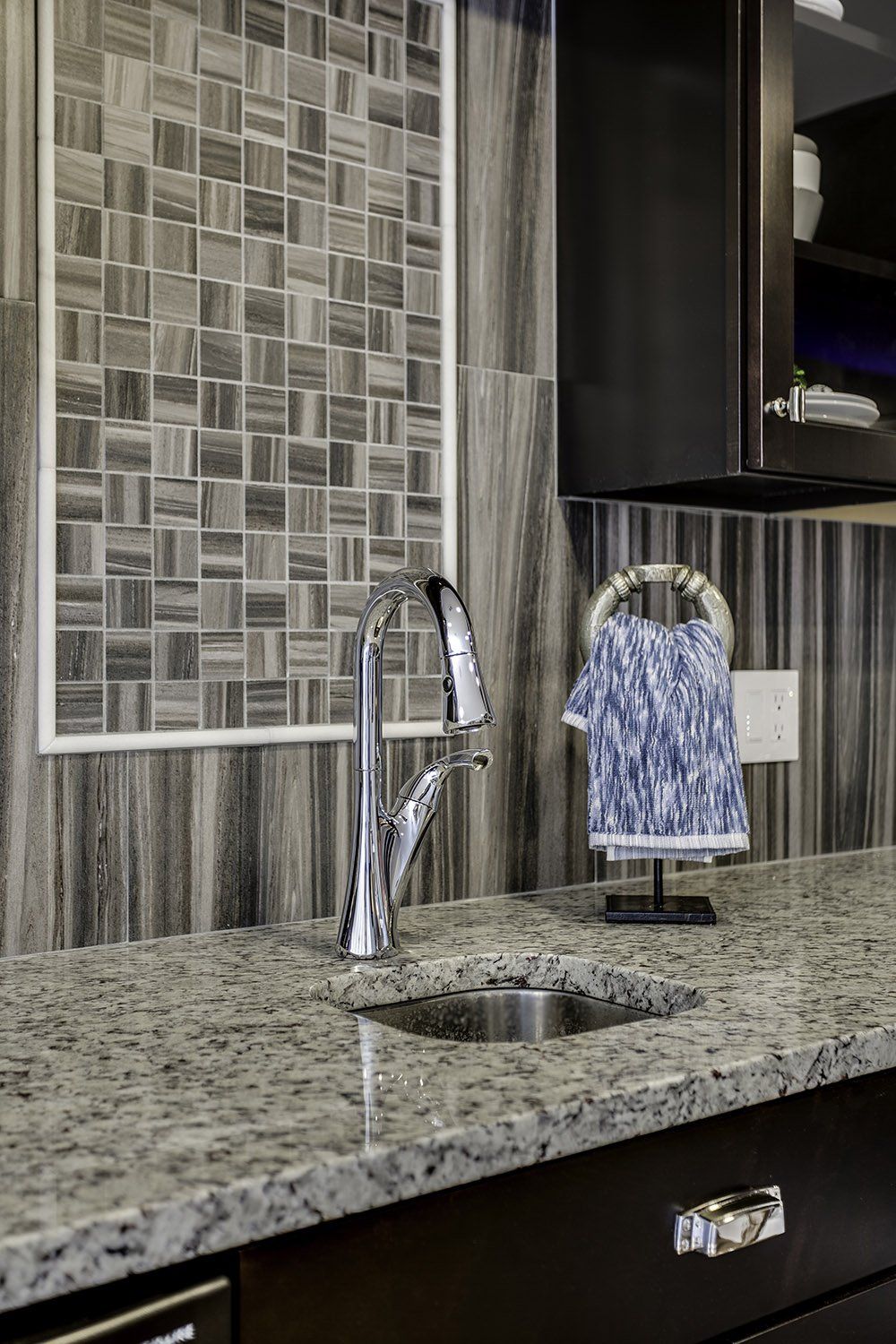 A kitchen sink with a faucet and a towel hanging on the counter.
