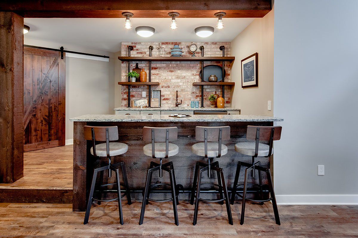 A bar with stools and a brick wall in a basement.