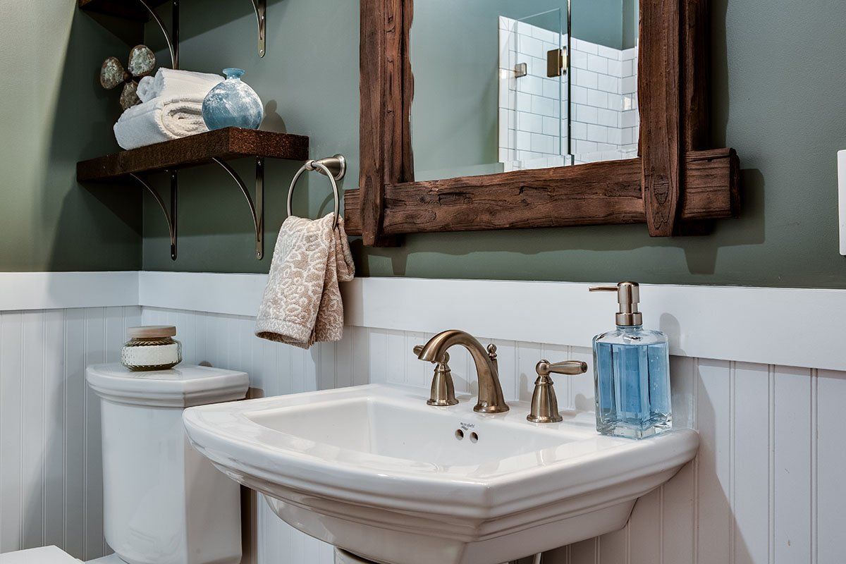 A bathroom with a sink , toilet , mirror and soap dispenser.