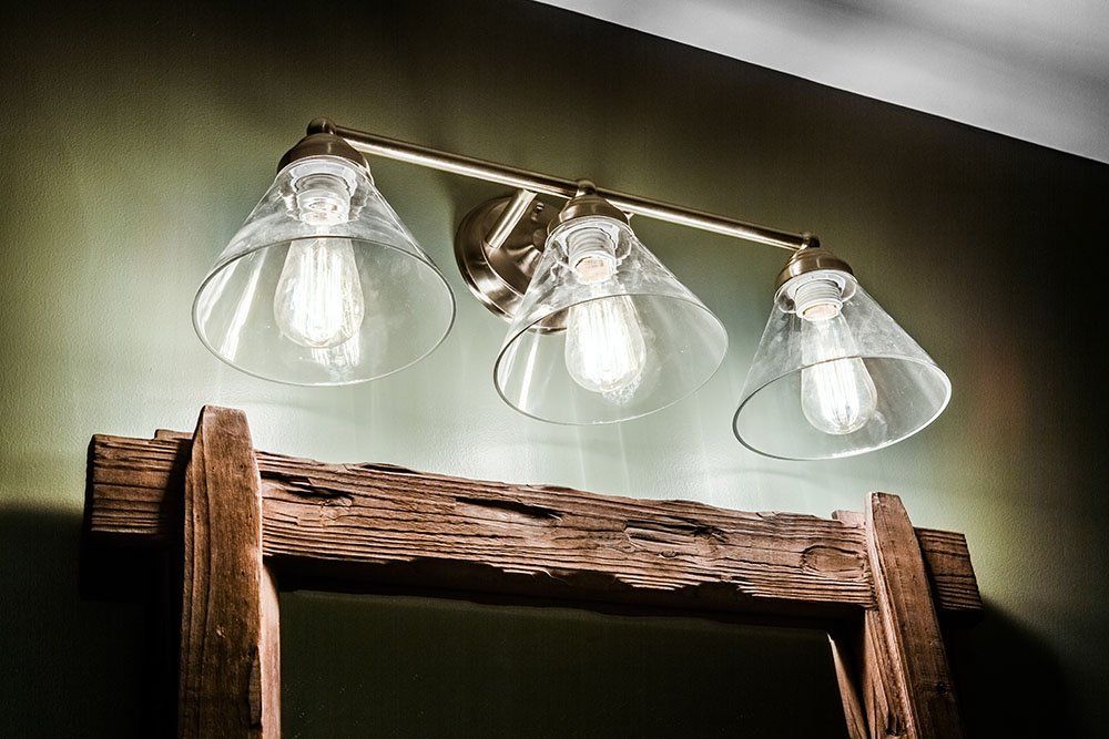 A bathroom vanity light with three clear glass shades