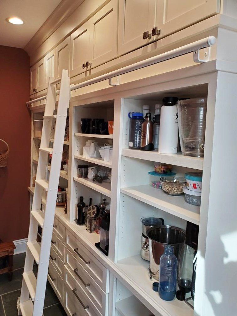 A kitchen with lots of shelves and a ladder