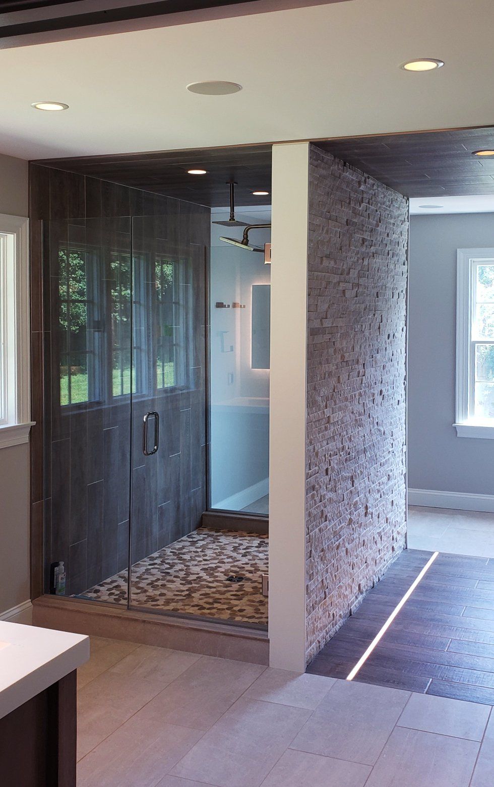 A bathroom with a walk in shower and a window.