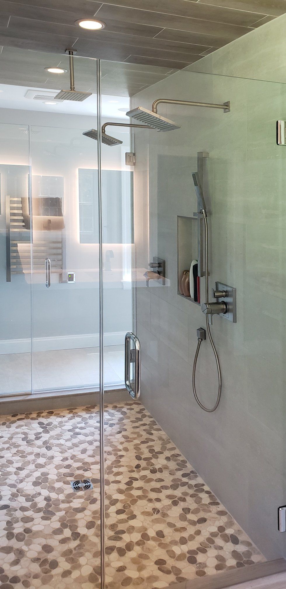 A bathroom with a walk in shower with a glass door and a shower head.